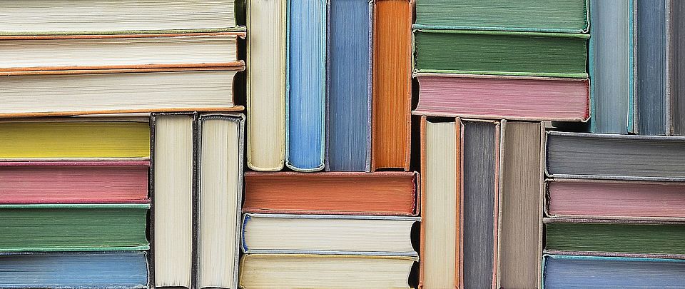 Bunte Bücher, in unterschiedlicher Position übereinandergestapelt